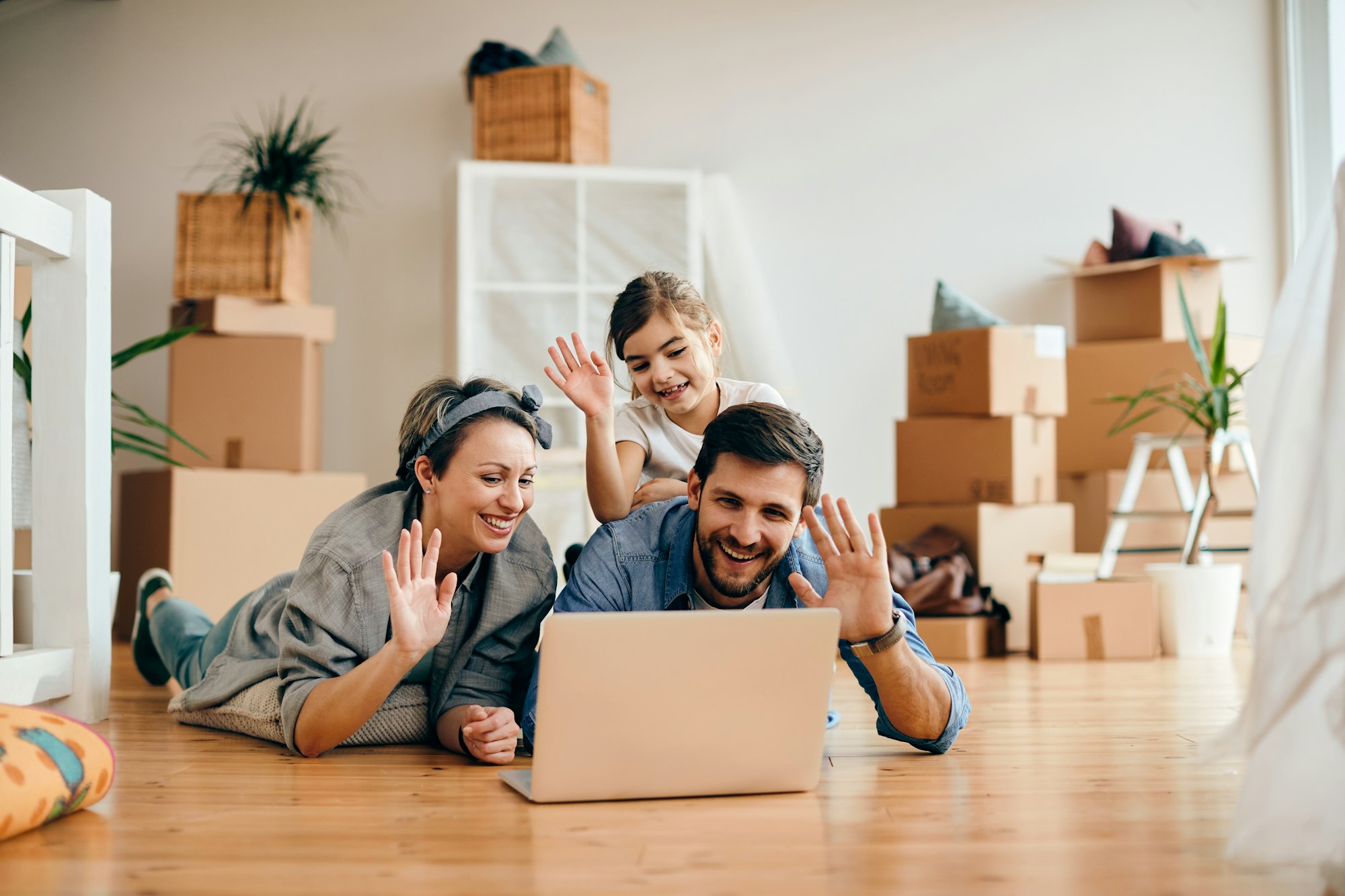 Happy family waving during a video call after moving into a new home.